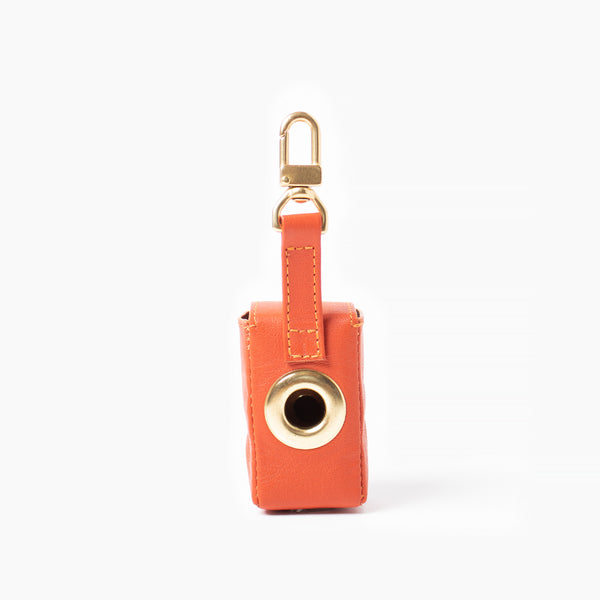 Orange leather bag holder with with brass hardware. Poop bag holder.